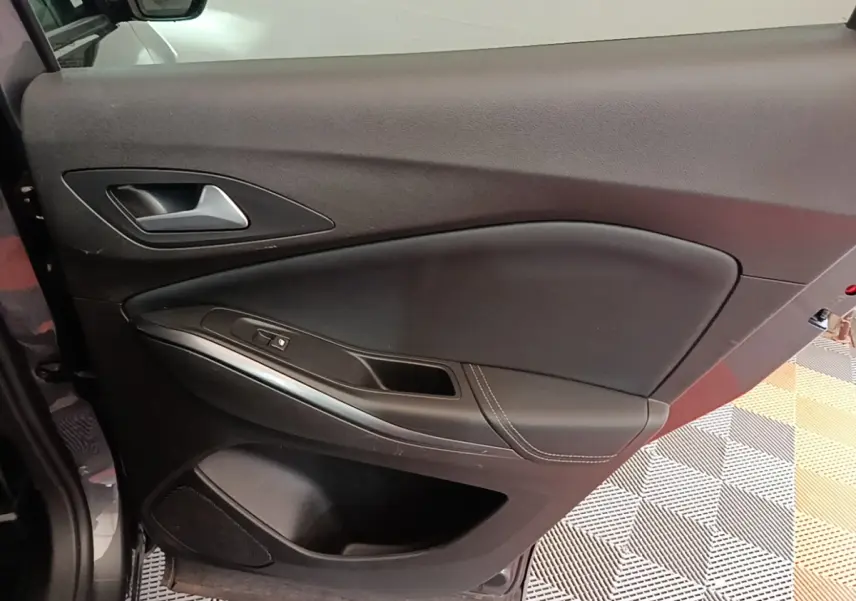 Intérieur de la porte côté gauche de l'Opel Grandland X gris foncé, avec poignée alu et commandes de vitre.