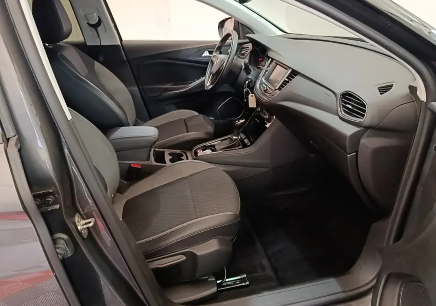 Intérieur avant droit de l’Opel Grandland X gris foncé, montrant sièges tissu, volant multifonctions et tableau de bord moderne.
