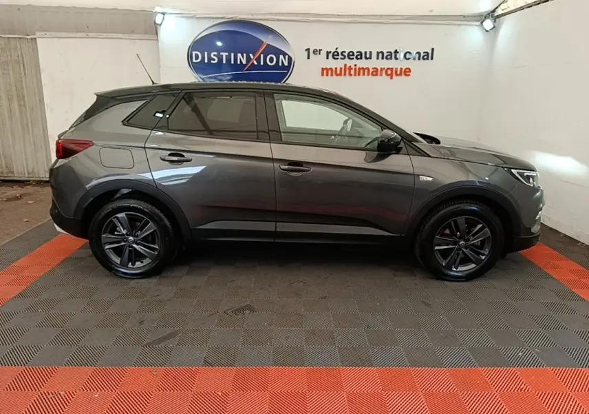 Vue latérale droite d'un Opel Grandland X gris foncé garé en intérieur avec jantes alliage noires.