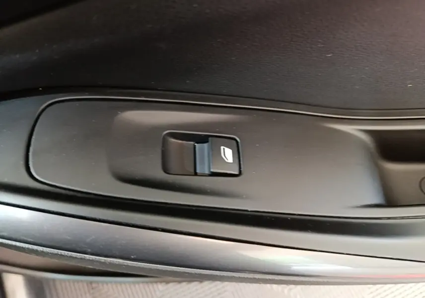 Gros plan sur le bouton de commande de lève-vitre côté porte intérieure d’un Opel Grandland X gris foncé.