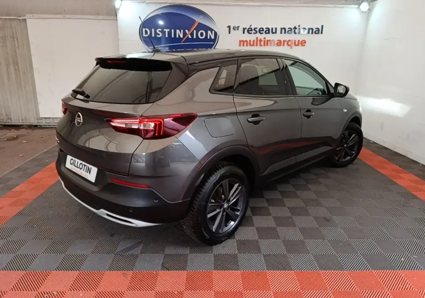 Opel Grandland X gris foncé en 3/4 arrière droit, avec jantes alliage et feux arrière LED visibles.