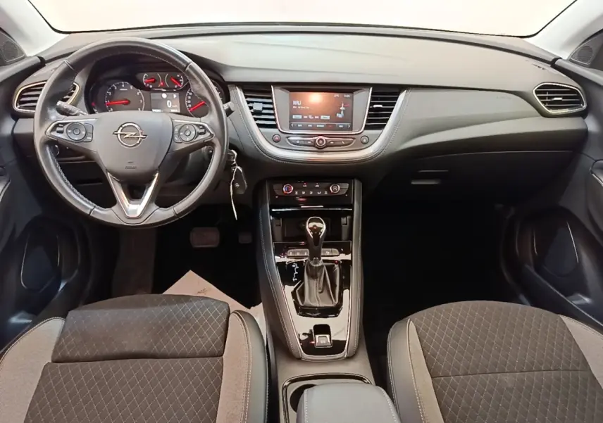 Vue intérieure avant de l'Opel Grandland X 1.5 Diesel gris, volant cuir multifonctions et console centrale avec boîte auto.