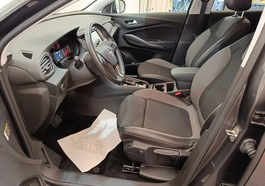 Vue intérieure côté conducteur de l'Opel Grandland X 1.5 Diesel gris foncé, volant multifonctions et sièges tissu bicolore.