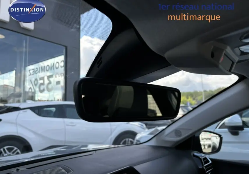 Vue intérieure du rétroviseur central d'une Citroën C4 gris Artense, avec tableau de bord et extérieur en arrière-plan.