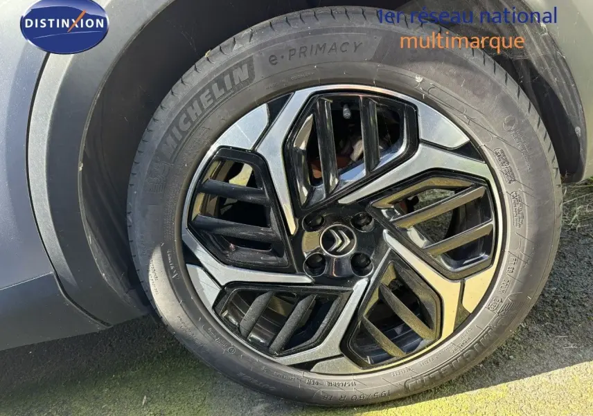 Gros plan sur la jante noire et argentée d'une Citroën C4 gris Artense, mettant en valeur le logo Citroën central.