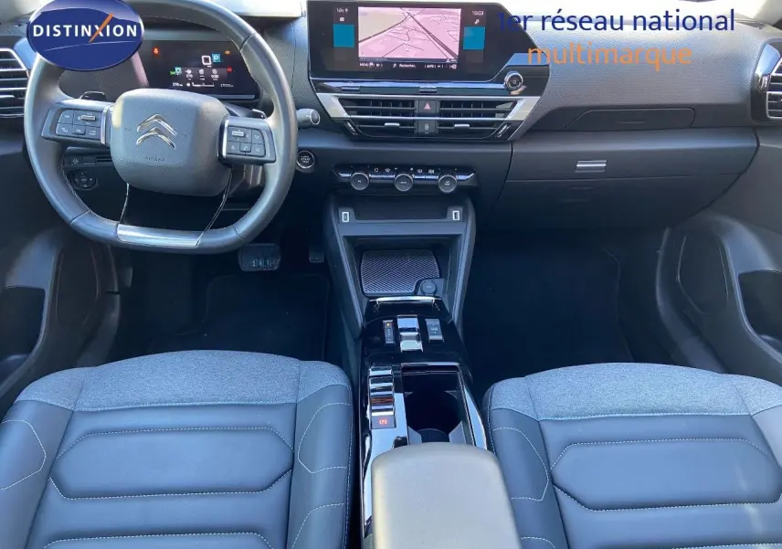 Vue intérieure avant de la Citroën C4 2022 avec tableau de bord moderne, écran tactile et sièges bi-matière gris et cuir noir.