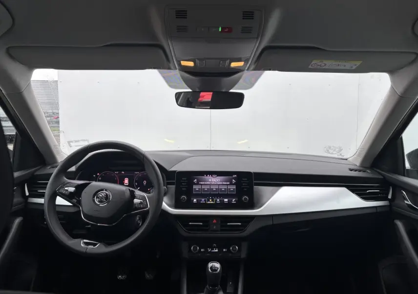 Intérieur avant du Skoda Kamiq 2024 avec tableau de bord noir, écran tactile central et volant cuir multifonctions.