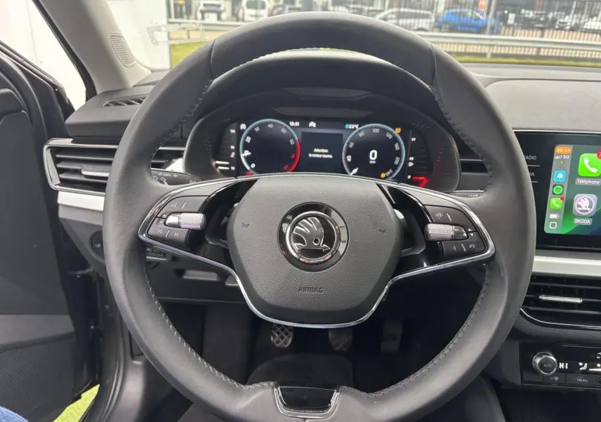 Vue centrée sur le volant cuir noir du Skoda Kamiq 2024 avec tableau de bord numérique et écran tactile latéral.