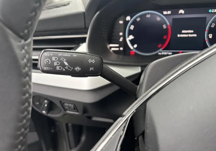 Gros plan sur la commande de régulateur de vitesse à gauche du volant cuir dans l'habitacle du Skoda Kamiq 2024.