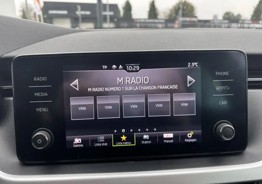 Écran tactile central du Skoda Kamiq 2024 affichant la radio M Radio avec commandes autour et finition gris graphite.