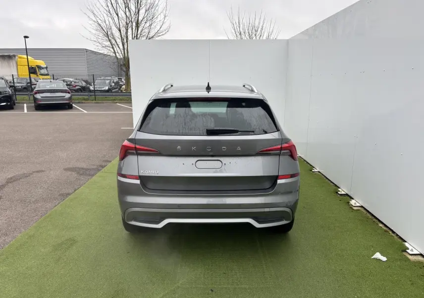 Vue arrière d'un Skoda Kamiq gris graphite métallisé avec feux LED et antenne aileron de requin sur parking.