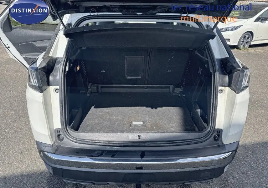 Coffre ouvert vu de l'arrière d'un Peugeot 3008 blanc nacré 2022 avec attelage visible sur parking.