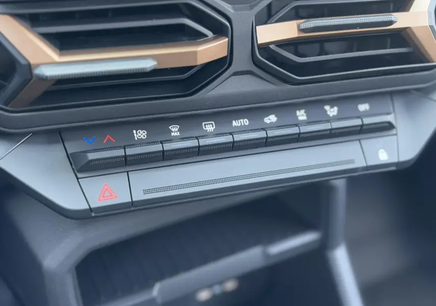 Boutons de commande de la climatisation et ventilation sur la console centrale du Dacia Duster noir nacré 2025.