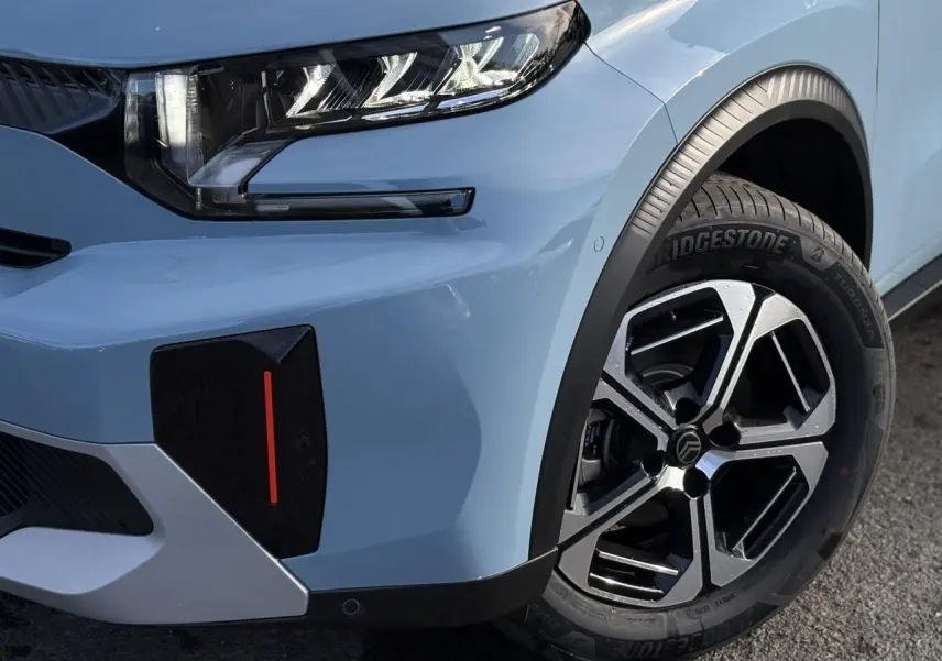 Gros plan sur l'avant droit bleu Monte Carlo du Citroën C3 Aircross Hybrid 2025 avec jante alliage diamantée et phare LED.