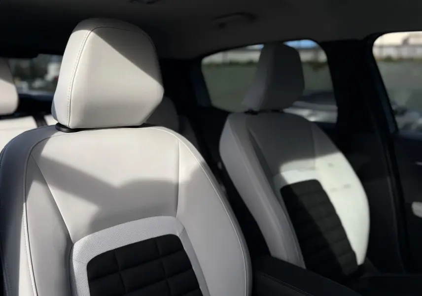 Gros plan sur les sièges avant gris clair et noir de la Citroën C3 Aircross Hybrid 2025, intérieur lumineux.