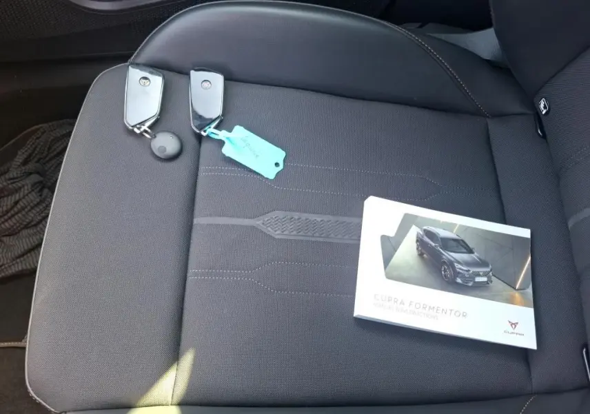 Vue rapprochée du siège avant droit gris foncé avec deux clés et le manuel d'instructions du CUPRA Formentor posé dessus.