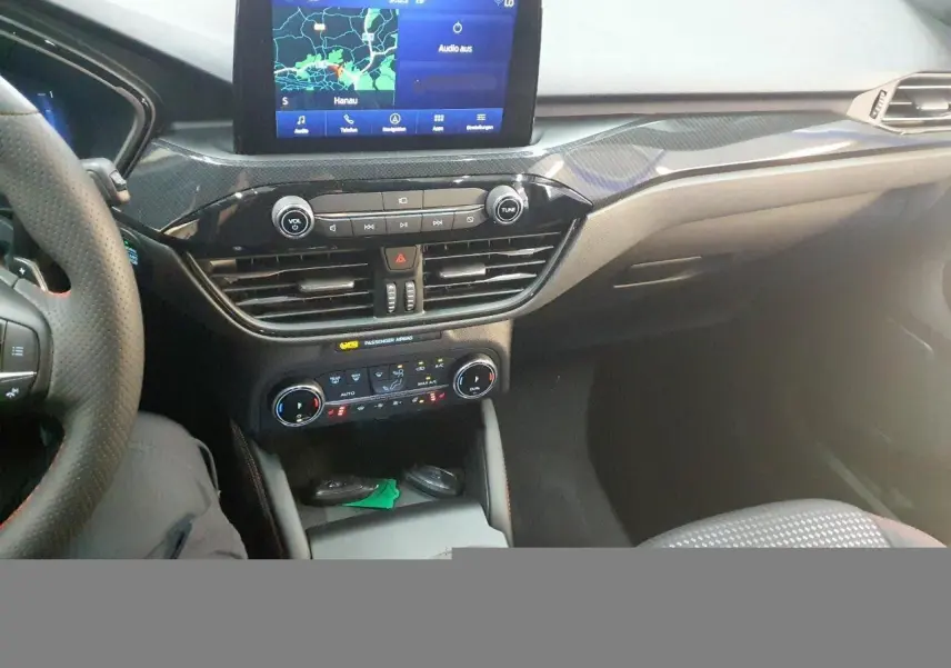 Vue intérieure du tableau de bord du Ford Kuga 2024, avec écran tactile GPS et commandes climatisation visibles.