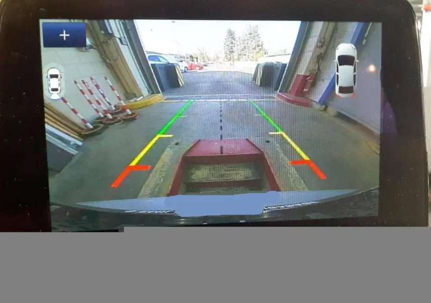 Vue caméra de recul du Ford Kuga gris Solar 2024 avec lignes de guidage colorées et affichage d'aide au stationnement.