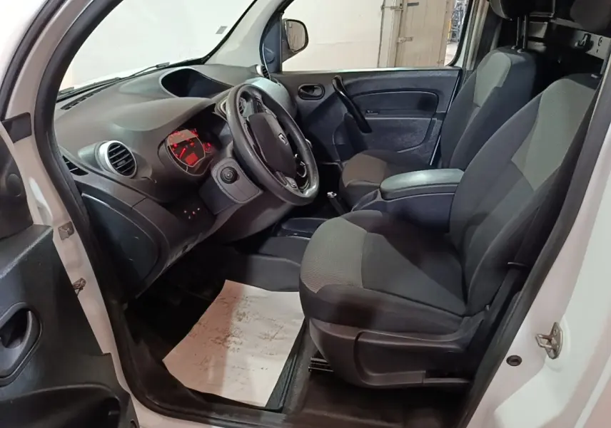 Intérieur avant droit du Renault Kangoo blanc 2020, montrant sièges tissu gris et tableau de bord avec volant réglable.