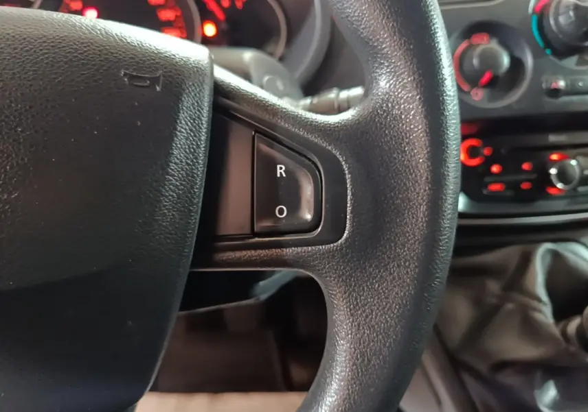 Gros plan sur le volant noir du Renault Kangoo 2020, avec tableau de bord et commandes rouges en arrière-plan.