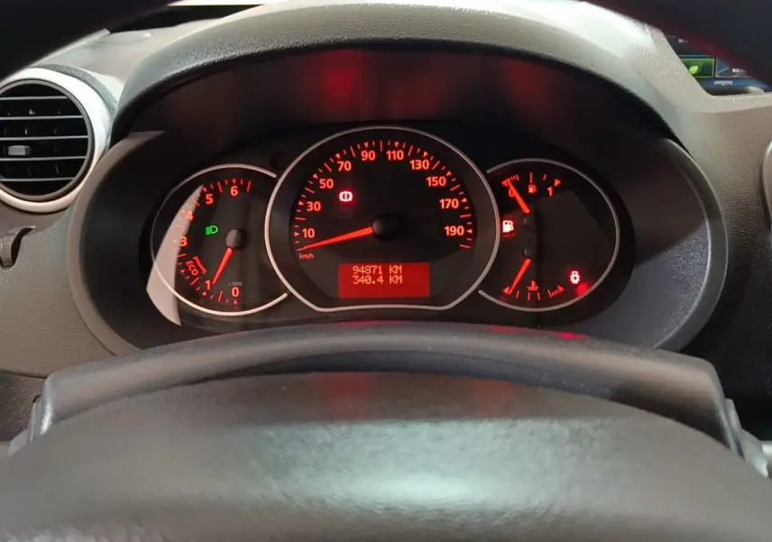 Vue rapprochée du tableau de bord du Renault Kangoo 2020, affichage rouge des compteurs derrière le volant noir.
