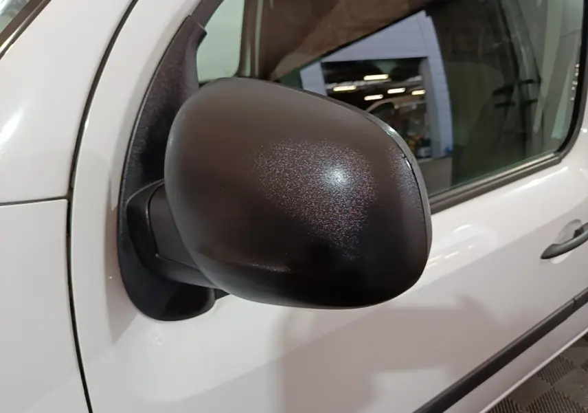 Rétroviseur noir en gros plan côté conducteur du Renault Kangoo blanc, vue latérale rapprochée.