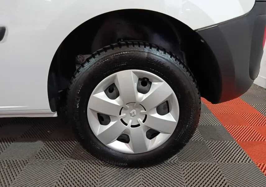 Gros plan sur la roue avant droite d’un Renault Kangoo blanc, avec enjoliveur argenté et pneu Continental.