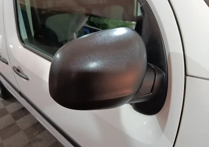 Rétroviseur noir en gros plan sur le côté gauche d’un Renault Kangoo blanc, vue latérale avant.