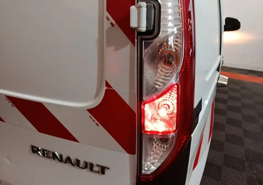 Gros plan sur le feu arrière droit d’un Renault Kangoo blanc avec marquages rouges en diagonale, vue arrière côté droit.
