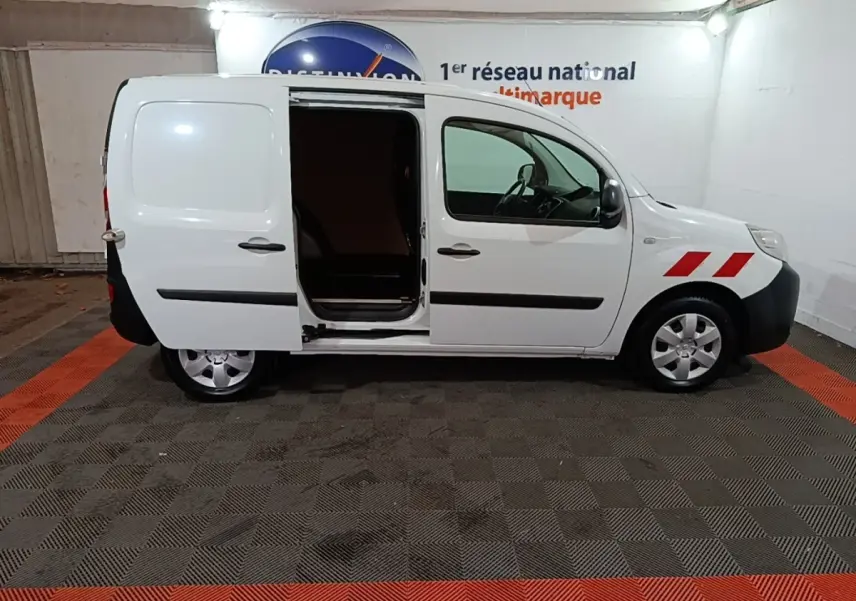 Vue de profil droit d’un Renault Kangoo blanc 2020 avec porte latérale coulissante ouverte et bandes rouges sur l’aile avant.
