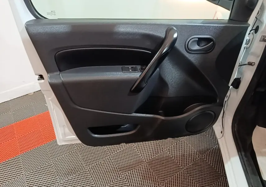 Vue rapprochée de la porte avant gauche blanche du Renault Kangoo 2020, montrant la poignée intérieure noire et les commandes de vitre.
