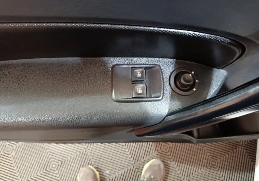 Gros plan sur les commandes de lève-vitres et réglage des rétroviseurs sur la porte côté conducteur du Renault Kangoo blanc.