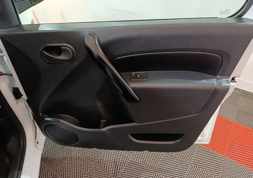 Vue rapprochée de la porte avant gauche noire du Renault Kangoo blanc, avec poignée intérieure et haut-parleur intégré.