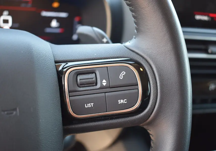 Gros plan sur les commandes gauche du volant en cuir noir du Citroën C5 Aircross 2024, avec boutons fonction téléphone et liste.