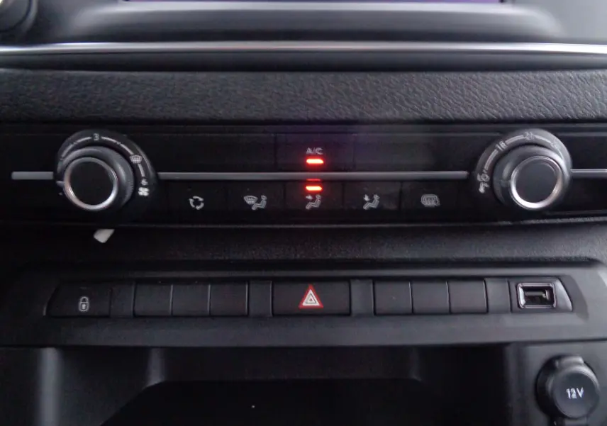 Gros plan sur la console centrale noire du Peugeot Expert Long 2023, avec commandes climatisation et boutons de fonction allumés.