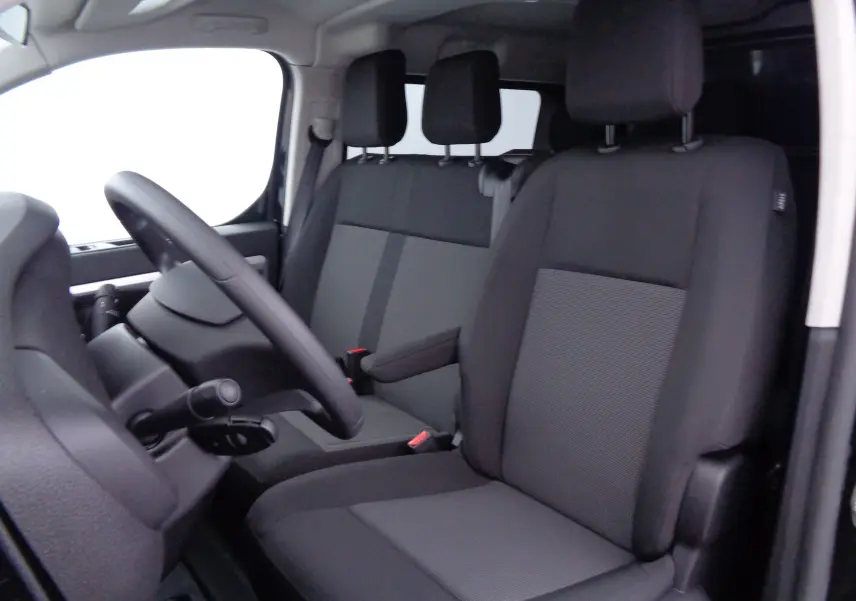 Vue intérieure côté conducteur du Peugeot Expert Long 2023, sièges tissu noir avec accoudoir central et volant visible.