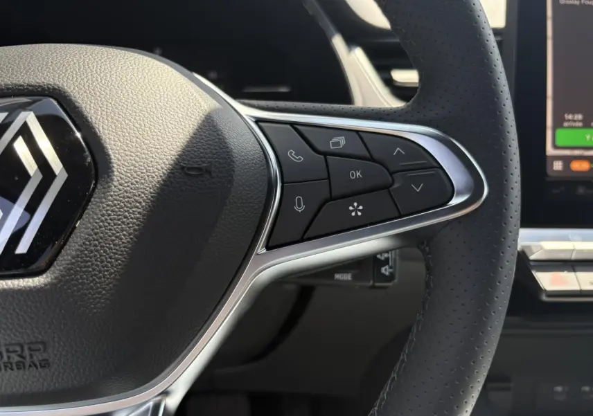 Gros plan sur le volant cuir multifonctions du Renault Captur noir étoile, avec commandes intégrées et tableau de bord numérique visible.