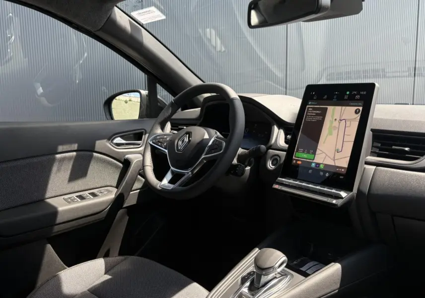 Intérieur noir du Renault Captur 2025 vu côté conducteur, avec volant multifonctions et écran tactile vertical affichant la navigation.