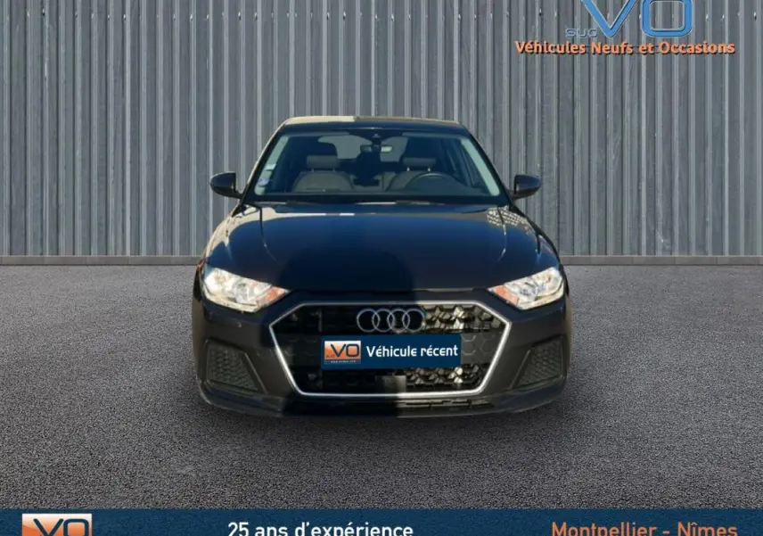 Vue frontale d'une Audi A1 Sportback gris foncé 2019 avec calandre hexagonale et phares halogènes allumés.