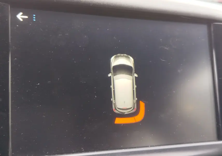 Affichage intérieur de la Peugeot 208 noir Perla Nera montrant l'alerte de proximité arrière droite sur l'écran de bord.