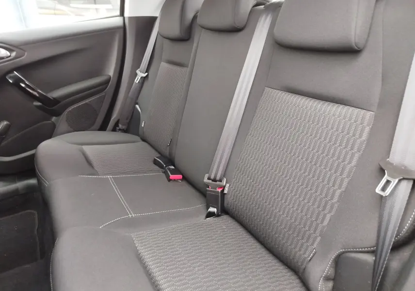 Vue intérieure de la banquette arrière noire de la Peugeot 208, avec ceintures de sécurité et appuie-têtes visibles.