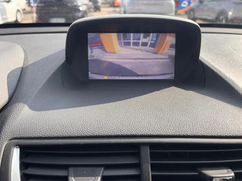 Vue intérieure sur l'écran de caméra de recul de l'Opel Mokka blanc, affichant l'arrière du véhicule en stationnement.
