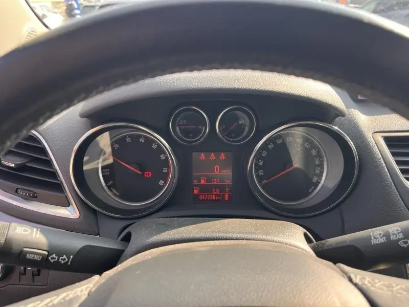 Vue du tableau de bord de l'Opel Mokka 2015, montrant les compteurs ronds et l'écran central rouge depuis le volant.