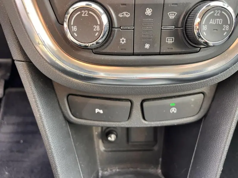 Gros plan sur la console centrale noire de l’Opel Mokka 2015, montrant les commandes de climatisation et boutons de stationnement et arrêt auto.