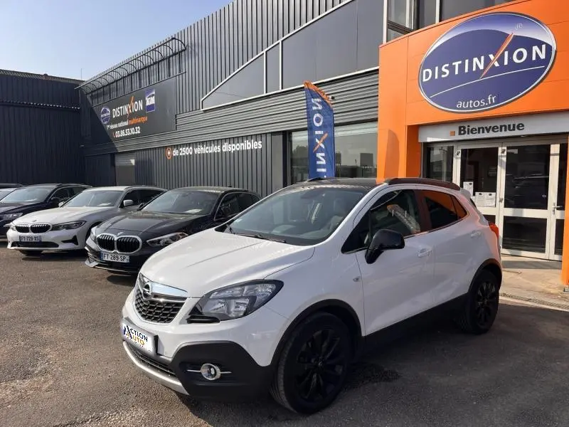Opel Mokka blanc Glacier vue 3/4 avant droit avec jantes noires, stationné devant un concessionnaire Distinxion.