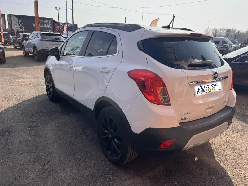 Opel Mokka blanc glacier vue 3/4 arrière droit avec jantes noires et vitres arrière teintées.