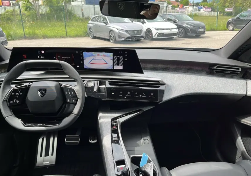 Vue intérieure avant du Peugeot 5008 Hybrid 145 GT Alcantara, tableau de bord moderne avec écran large et volant compact cuir.