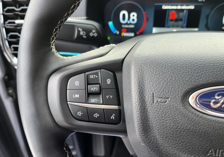 Gros plan sur le volant cuir multifonctions du Ford Ranger 2026, avec commandes de régulateur et tableau de bord numérique visible.