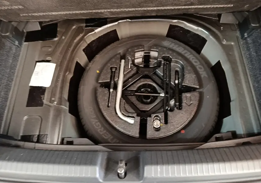 Vue plongeante sur la roue de secours et les outils de bord dans le coffre d'une Volkswagen Polo noire 2020.