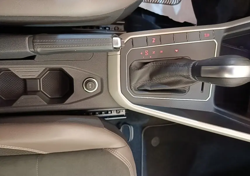 Vue intérieure centrée sur la console centrale de la Volkswagen Polo noire, avec levier de vitesse automatique et frein à main cuir.
